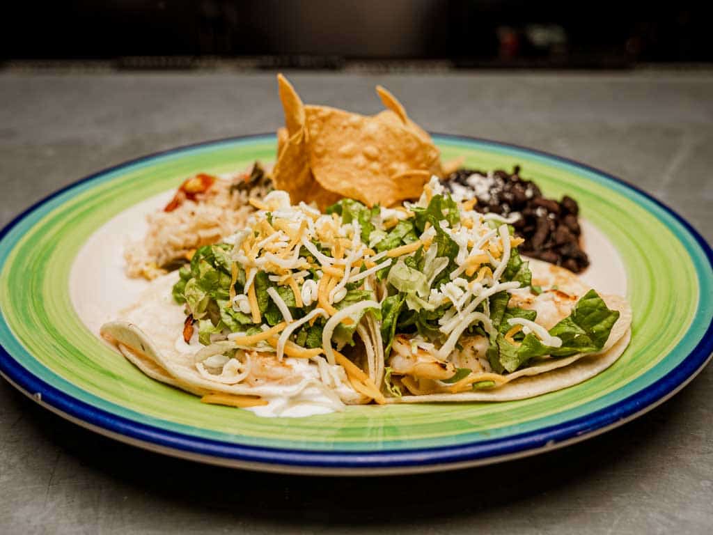 Two charbroiled shrimp tacos in a soft corn tortilla with lettuce, cheese & special white sauce.